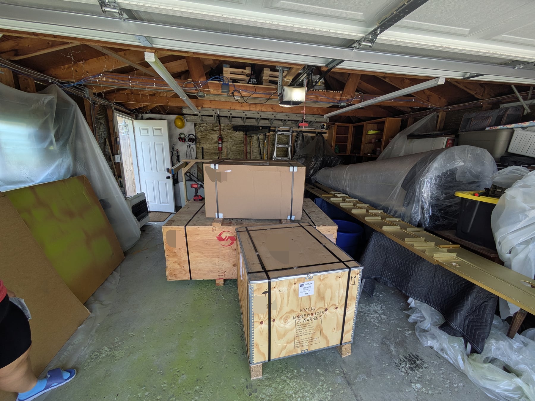 The two powerplant boxes and finishing kit delivered into the garage. You can see the wing spars and the finished empennage also in the garage.